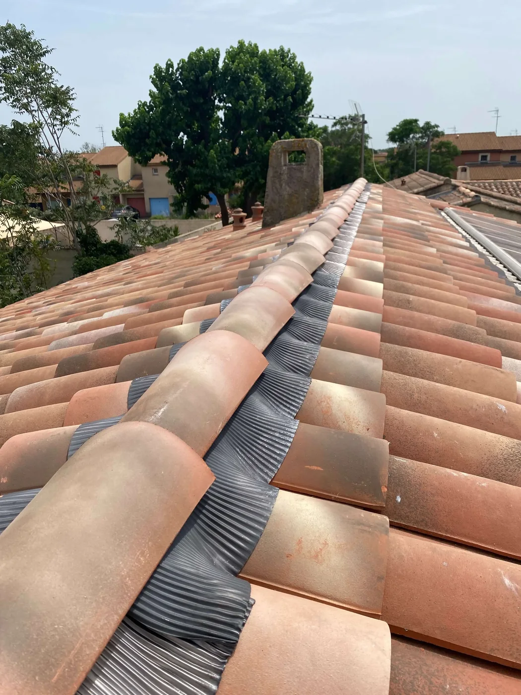 Faîtières en terre cuite et closoir ventilé sur un toit en tuiles