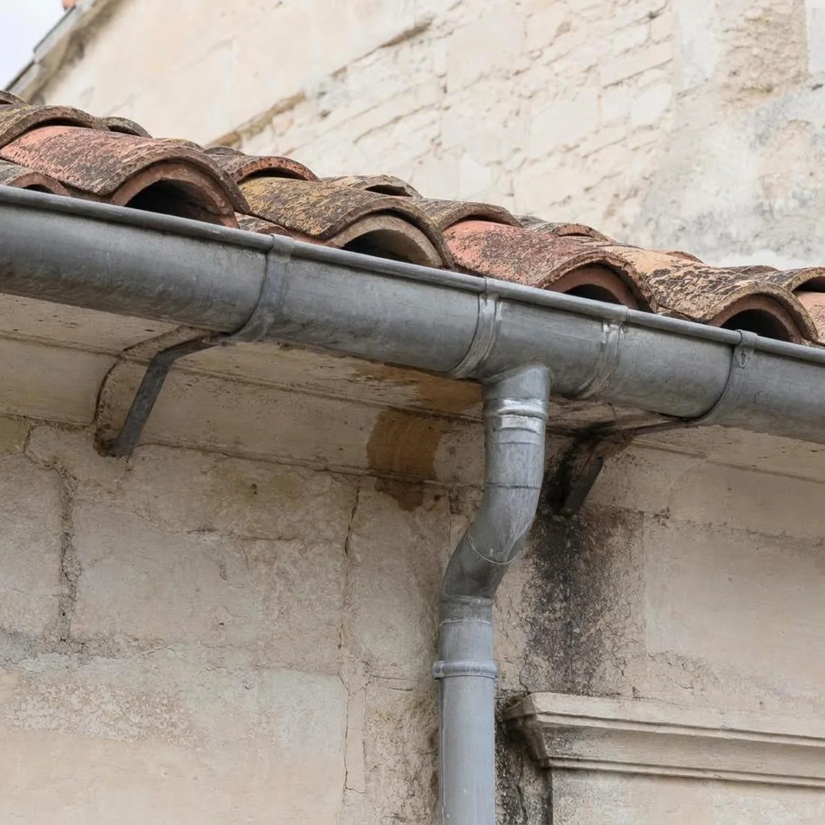 Gouttière en zinc fixée en bas d'un pan de toiture en tuiles